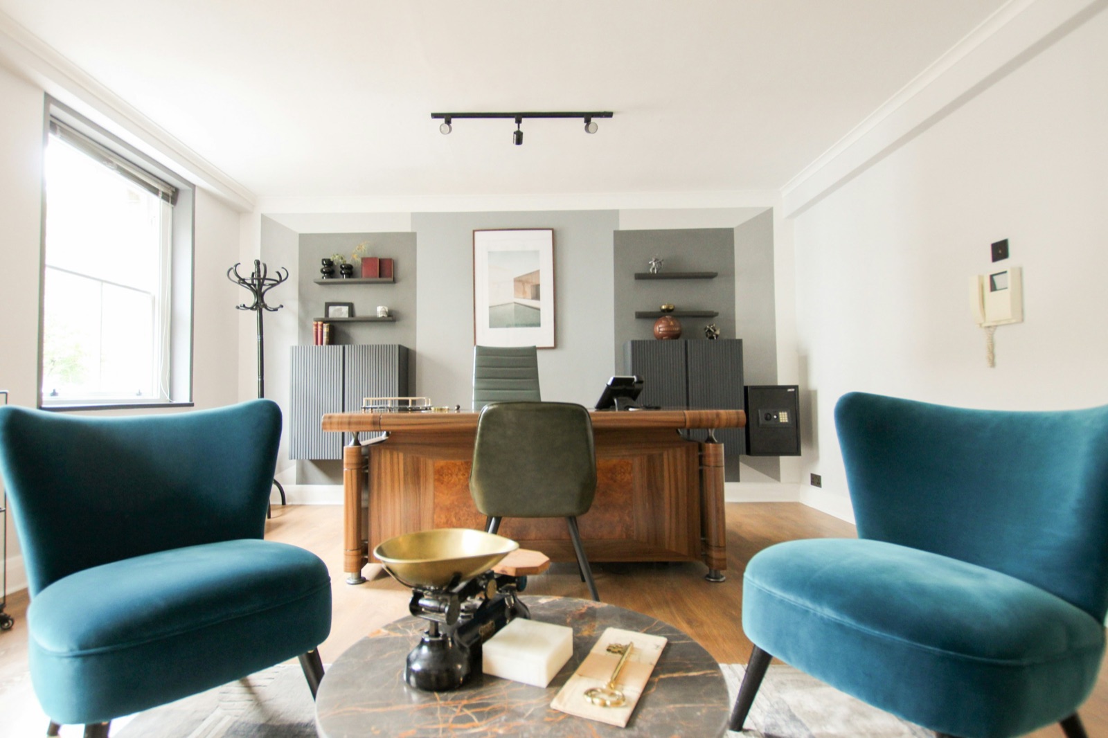 A bright agency office with a desk and two armchairs