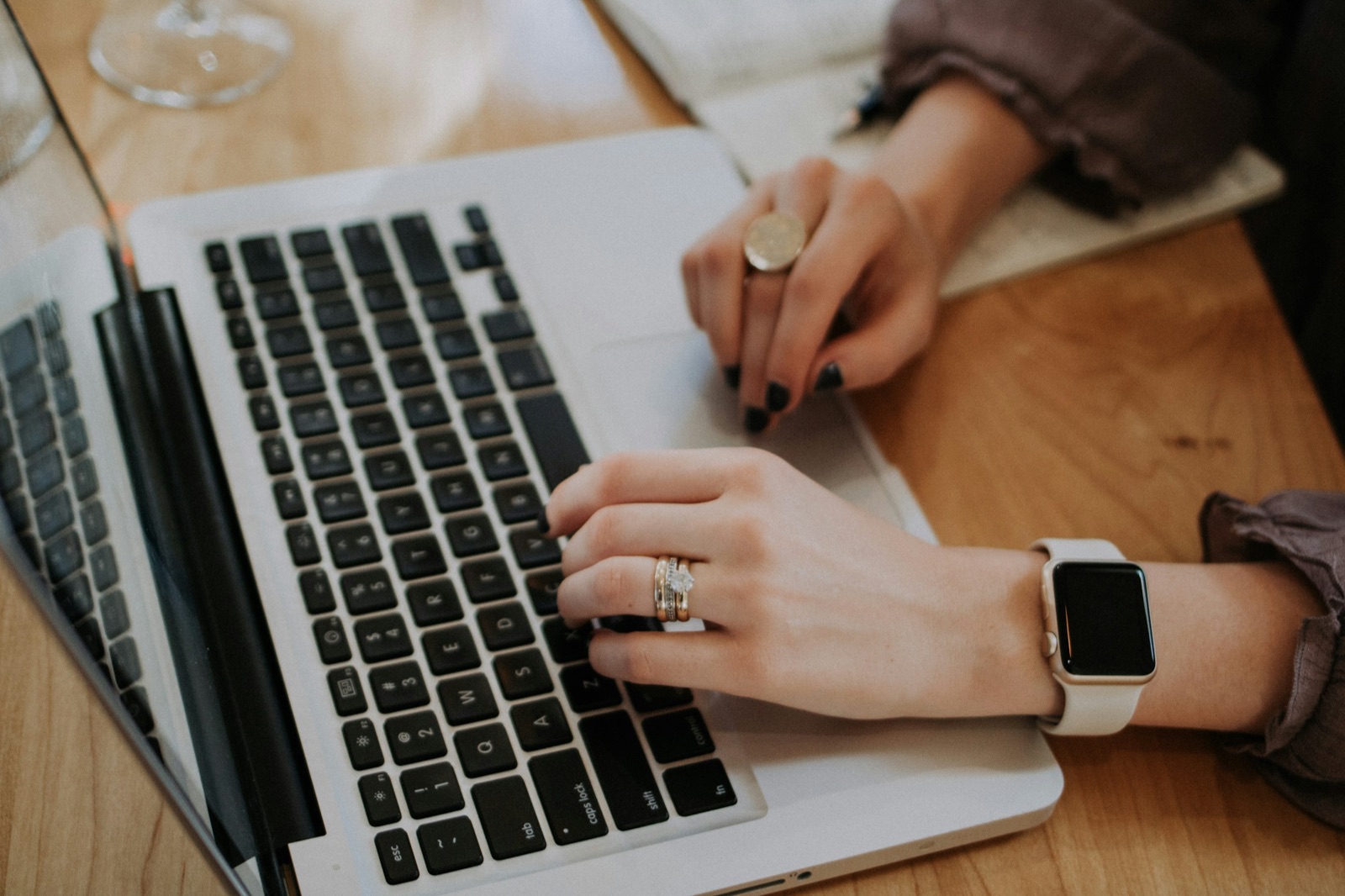 Hands typing on a laptop at a wooden desk